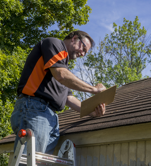 Contractor Using Clipboard To Figure Hail Damage Repair Costs